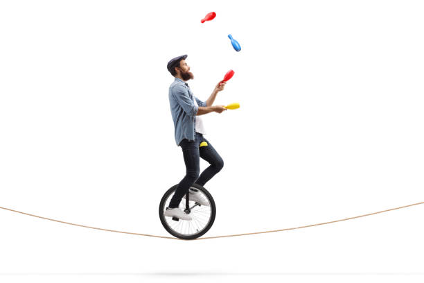male juggler with clubs riding a unicycle on a rope - unicycle unicycling cycling wheel imagens e fotografias de stock