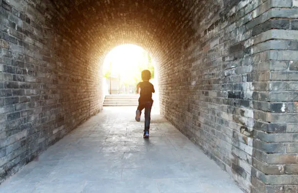 Little boy running through the tunnel.