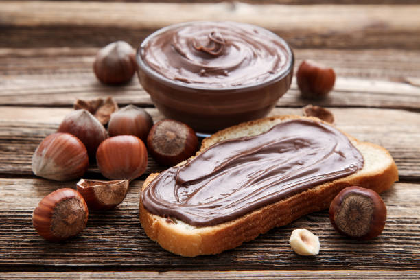 istock Bread with melted chocolate and hazelnuts on brown wooden table 1156917379