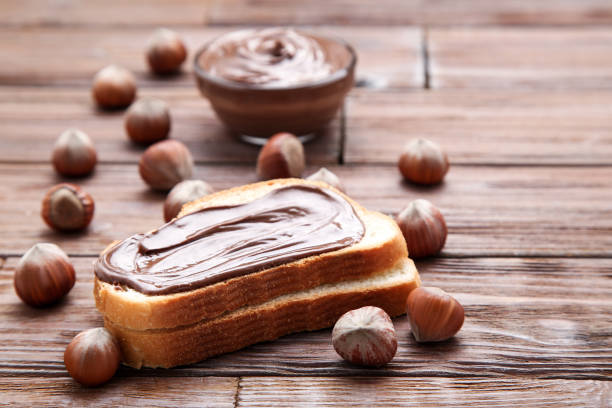 istock Bread with melted chocolate and hazelnuts on wooden table 1156917625