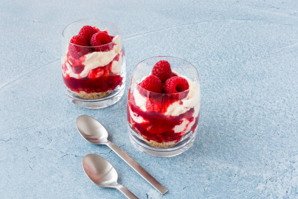istock Raspberry Dessert in Glasses and Spoons on Blue Background 1156920762