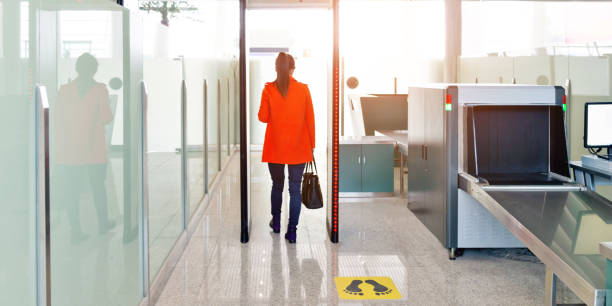 Female passenger walking through the airport security checkpoint Female passenger walking through the airport security checkpoint. metal detector security stock pictures, royalty-free photos & images