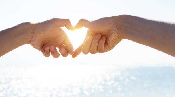 istock Two hands create a heart symbol on the beach 1156924927