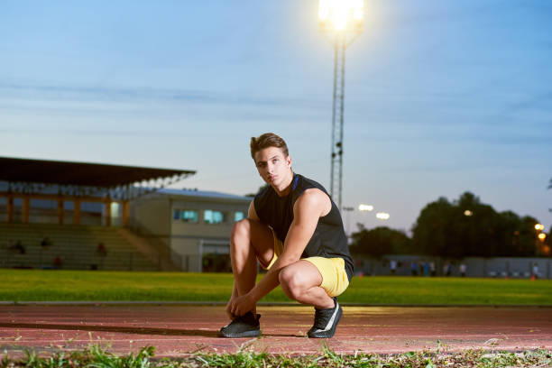 istock Young man runner tying shoelaces on stadium. 1156925107