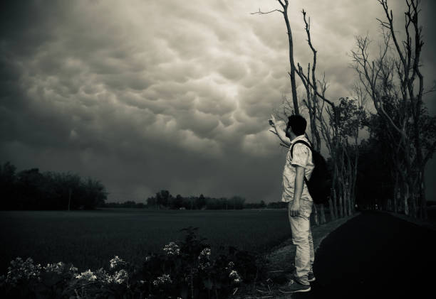 Man raising hands showing dark clouds in the sky unique stock photo