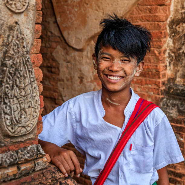 Young Burmese schoolboy with thanaka standing in the ancient temple of Bagan, Myanmar (Burma)