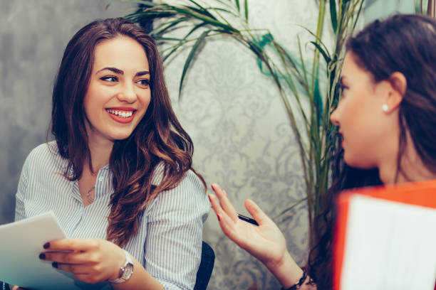 istock Two young women talking and drinking coffee while analyzing strategy of their work on paper documents 1156926933
