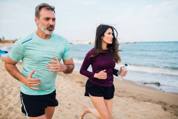 pares atléticos que movimentam-se na praia - couple stretching running jogging - fotografias e filmes do acervo