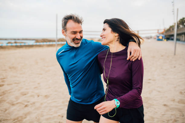 joggers étreignant sur la plage - senior couple audio photos et images de collection