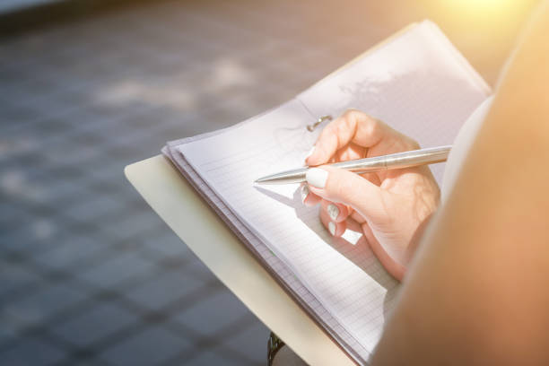 istock female hand takes notes in a notebook in nature 1156932252