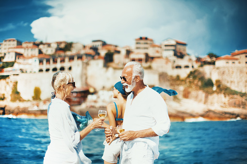 Senior couple drinking white wine, holding hands and enjoying sailing cruse.