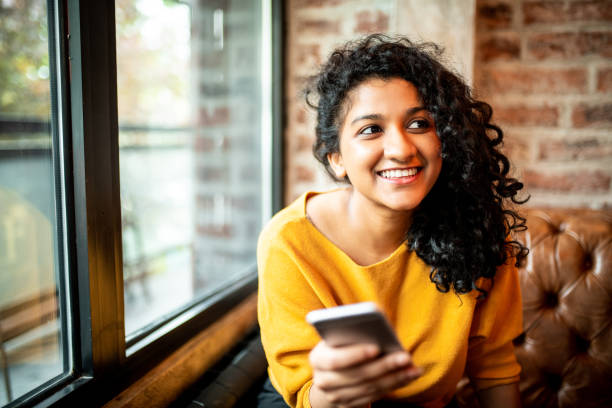 Using mobile phone. Young Indian woman using mobile phone at the bar person paying stock pictures, royalty-free photos & images