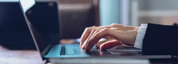 Photo of Close up of business woman hands typing on laptop computer and searching web, browsing in the workplace at office. proportion of the banner for advertisement.