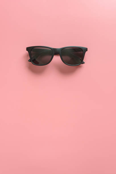 Black stylish sunglasses on pink background. Flat lay. Minimal style concept