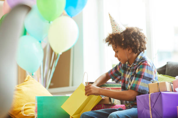アフリカ系アメリカ人の男の子が誕生日プレゼントを開く - 誕生日の贈り物 ストックフォトと画像