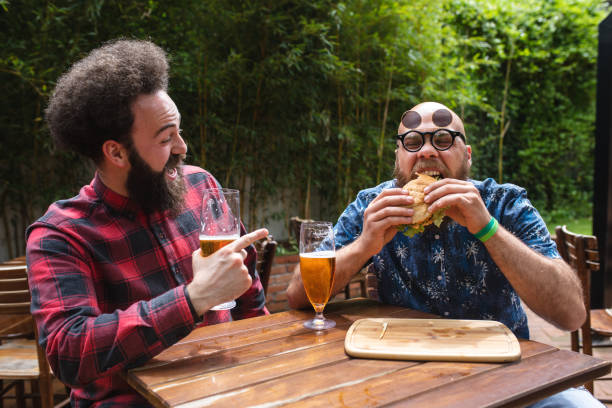 istock Hipsters having fun eating burgers and drinking beer 1156939185