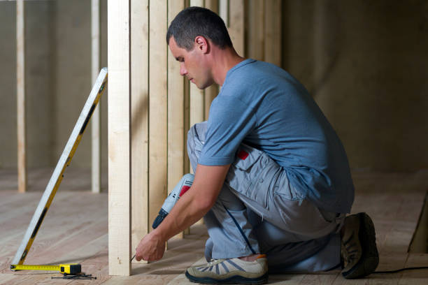 istock Young professional worker uses level and screwdriver installing wooden frame for future walls. Interior of attic insulated room with oak floor under reconstruction.  Renovation and improvement concept. 1156942407