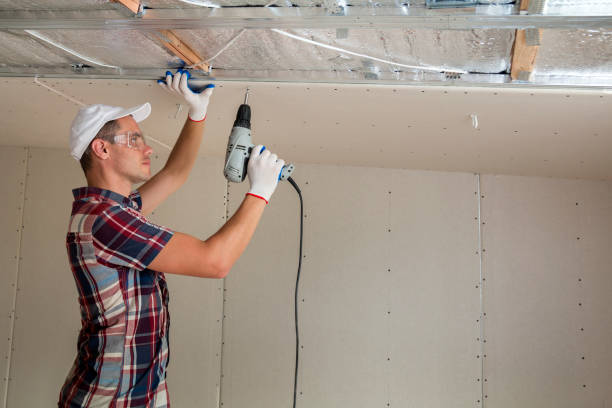 istock Young man in goggles fixing drywall suspended ceiling to metal frame using electrical screwdriver on ceiling insulated with shiny aluminum foil. Renovation, construction, do it yourself concept. 1156942534