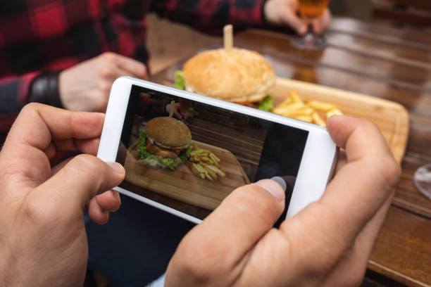 istock Man photographing a burger and fries 1156943501