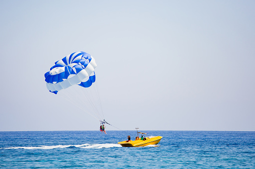 Photographer making a photo of couple of tourists flying on a blue and white parachute