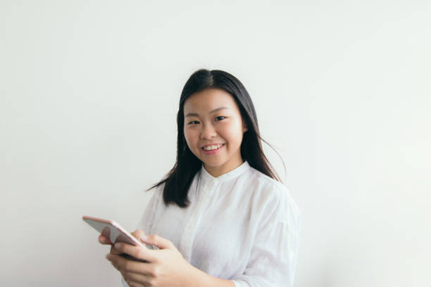 istock Asian Corporate Female smiling while holding smart phone 1156953686