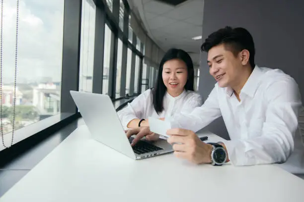 Photo of Asian Male and female discussing about business in front of laptop