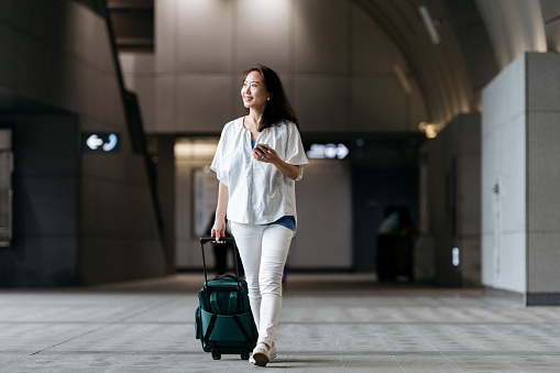 Smiling senior woman arriving in airport and using mobile phone, technology, travel, on the go