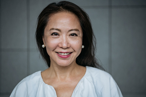 Headshot of businesswoman in her 60s looking at camera, confidence, cheerful, beauty