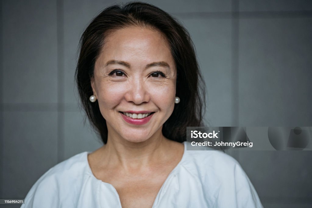 Attractive senior Chinese woman smiling Headshot of businesswoman in her 60s looking at camera, confidence, cheerful, beauty Women Stock Photo