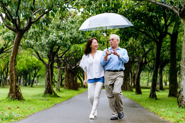 istock Senior couple talking in rain under umbrella 1156954224