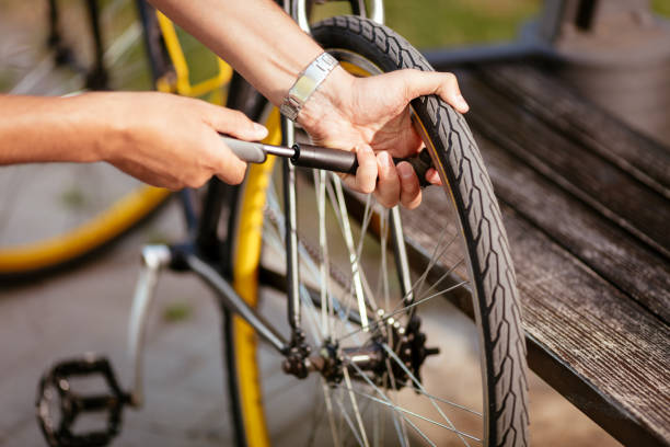 Inflate A Bike Tire Close-up of a man pumping bicycle wheel on the street. air pump stock pictures, royalty-free photos & images