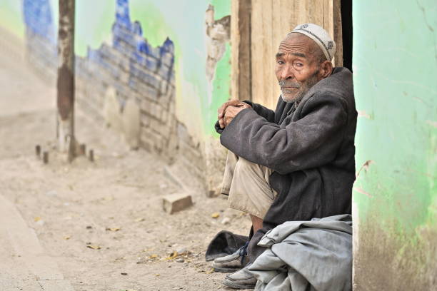 сторона глядя уйгурский старик сидит на двери lintel-животноводства рынке-хотан-синьцзян-китай-0157 - uighur стоковые фото и изображения