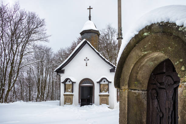 Small, snow-covered chapel with prayer stone in the foreground in a winter landscape in Winterberg, Sauerland, Hochsauerland, Germany. Small, snow-covered chapel with prayer stone in the foreground in a winter landscape in Winterberg, Sauerland, Hochsauerland, Germany. winterberg photos stock pictures, royalty-free photos & images