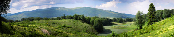 Mountains landscape panorama. Fluffy clouds over a mountain range Mountains landscape panorama. Fluffy clouds over a mountain range, alpine meadow on a sunny summer day. Travel in Georgia georgia landscape stock pictures, royalty-free photos & images