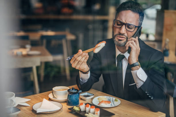 istock Man in the sushi restaurant using phone 1156970348