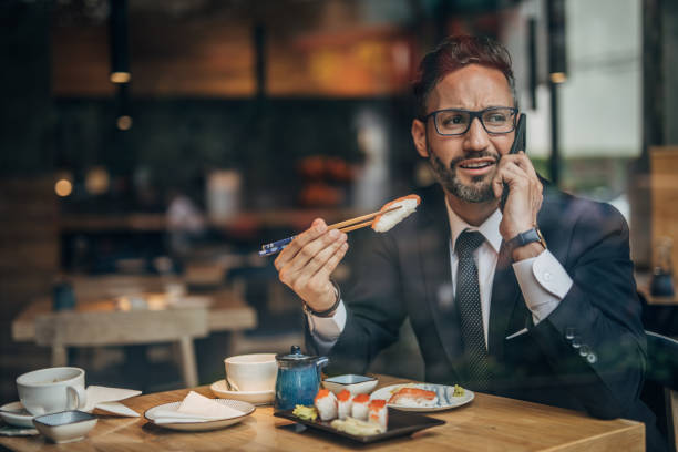 istock Man in the sushi restaurant using phone 1156971403