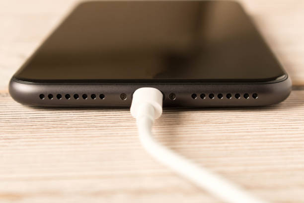 istock Smartphone on charge . On the  wooden table . Close up. 1156975556