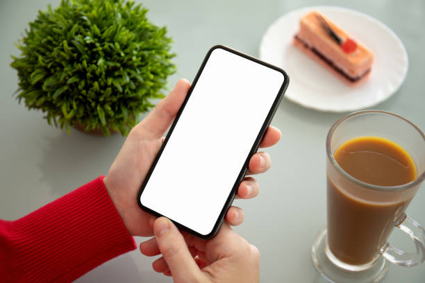 istock female hands holding phone with isolated screen in a cafe 1156977065