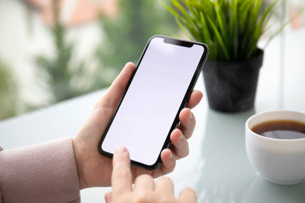 istock female hands holding phone with isolated screen in summer cafe 1156977650