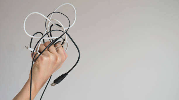 istock Black and white cables in a left woman's hand on a light gray background 1156981169