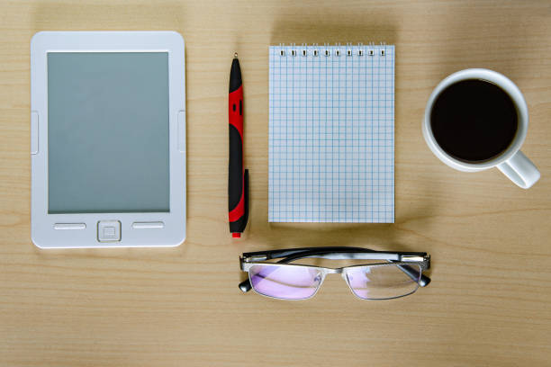istock Office table. Tablet, glasses, notebook and pen cup of coffee. Wooden table. Top view 1156982326