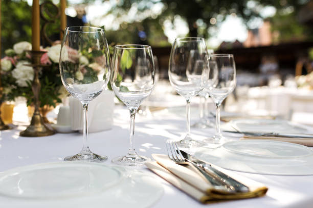 istock Wedding table setting decorated with fresh flowers in a brass vase. Wedding floristry. Banquet table for guests outdoors with a view of green nature. Bouquet with roses, eustoma and eucalyptus leaves. 1156986428