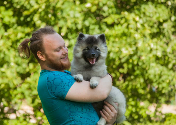 istock Young man and keeshond puppy 1156987487