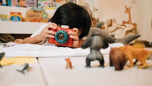 Photo of Asian toddler girl photographer playing with toy camera.