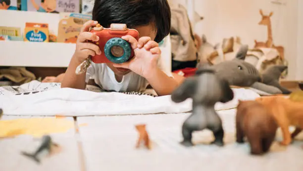 Photo of Asian toddler girl photographer playing with toy camera.