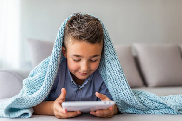 istock Little cute boy playing games on a tablet and watching cartoons 1156992027