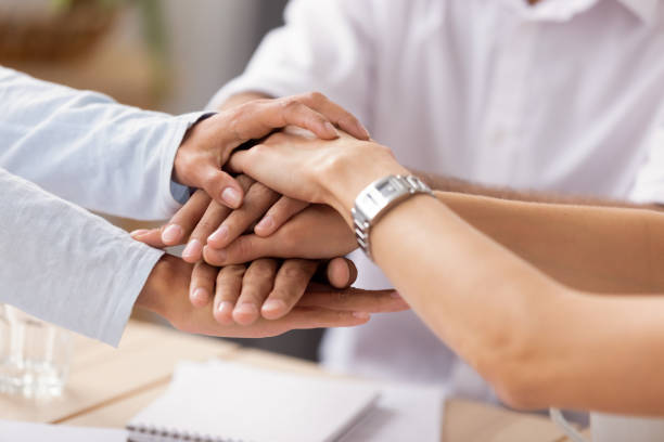 istock Close up view diverse business people putting stacked hands together 1156995119