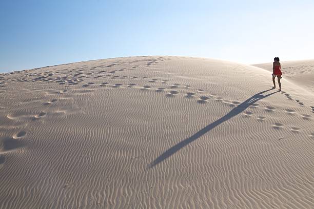 istock woman and shadow up the dune 115699540