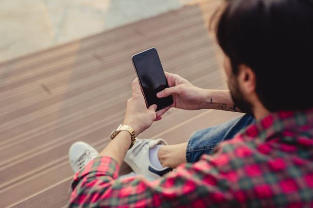 istock a young man uses smartphone while standing outdoor 1156996306
