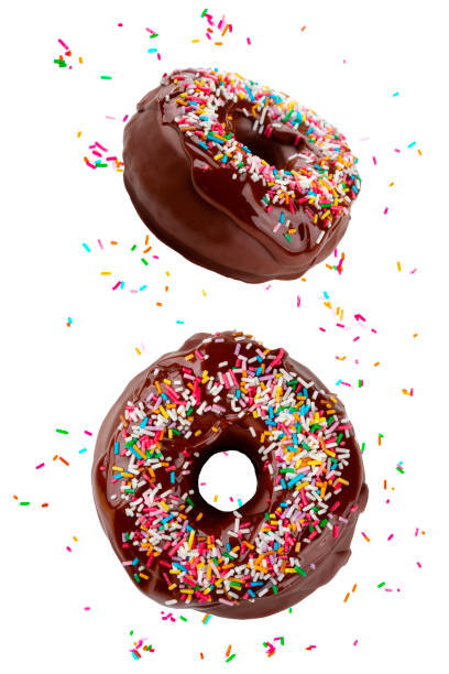 istock Delicious fresh chocolate donuts decorated with sprinkles falling between more colored sprinkles 1156997859